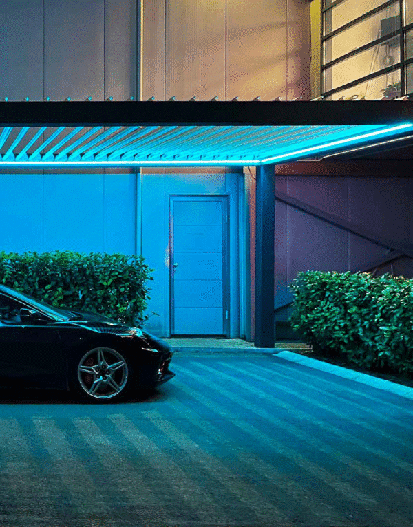 Pergolă premium EurosanDOOR cu iluminare LED, vedere nocturnă cu partea dreaptă a unei mașini parcată dedesubt.